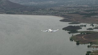 CBAX01_024 - HD aerial stock footage of tracking Cessna 340 over Lake Mathews, hazy, Perris, California