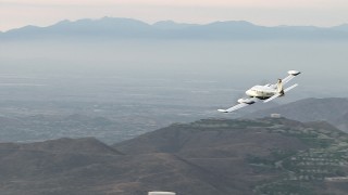 CBAX01_025 - HD aerial stock footage of flying by hazy hills, revealing Cessna 340, Perris, California