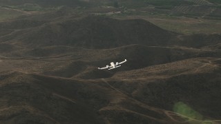 CBAX01_028 - HD aerial stock footage of tracking Cessna 340 over hills then out of frame on hazy day, Perris, California