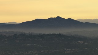 CBAX01_090 - HD aerial stock footage of Hollywood Sign through smog from a distance, Hollywood, California, sunset