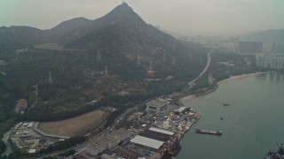 DCA02_057 - 4K aerial stock footage tilt from warehouse buildings to reveal Castle Peak and waterfront apartments, New Territories, Hong Kong, China