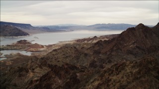 DCA04_082 - 4K aerial stock footage of flying over rocky ridge in Hiller Mountains, revealing Lake Mead, Nevada