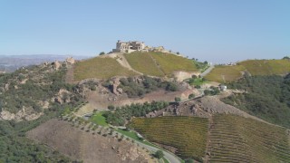 DCA05_137 - 4K stock footage aerial video of pan across hills, revealing vineyard, hilltop winery, Malibu, California