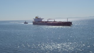 DCA06_032 - 4K aerial stock footage fly low over ocean to approach oil tanker, tugboat, Long Beach, California