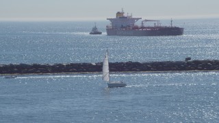 DCA06_034 - 4K aerial stock footage of a sailboat, oil tanker, and tugboat near breakwater, Long Beach, California