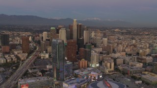 DCA07_012 - 4K aerial stock footage of flying by Downtown skyscrapers, over Highway 110, mountains in the distance, Los Angeles, California, twilight