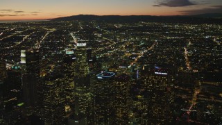 DCA07_052 - 4K aerial stock footage of flying by Downtown skyscrapers, view of Los Angeles Basin, Santa Monica Mountains, California, twilight