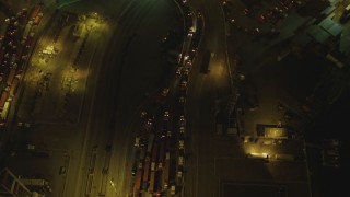 DCA07_128 - 4K aerial stock footage of flying over trucks lined up at Port of Long Beach, California, night