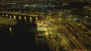 DCA07_132 - 4K aerial stock footage of flying by cargo ship, cranes, containers, Port of Long Beach, California, night