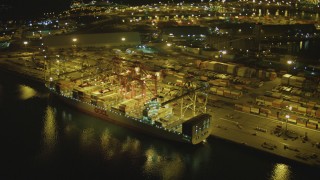 DCA07_133 - 4K aerial stock footage of flying by a cargo ship, cranes, containers, Port of Long Beach, California, night