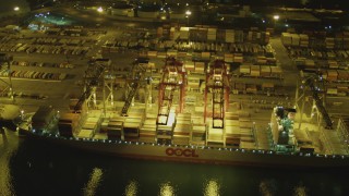 DCA07_137 - 4K aerial stock footage fly over cargo ship, cranes, containers at Port of Long Beach, California, night