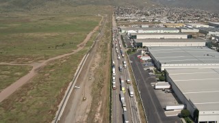DCA08_072E - 4K stock footage aerial video fly over warehouses and trucks by border fence, US/Mexico Border, Tijuana