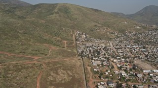 DCA08_074E - 4K aerial stock footage video follow the border fence toward a mountain, US/Mexico Border, Tijuana