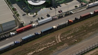 DCA08_080 - 4K aerial stock footage of a ling of big rigs by a warehouse, Tijuana, Mexico