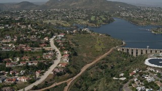 DCA08_134 - 4K aerial stock footage flyby water treatment plant, dam and lake to reveal upscale homes, Del Cerro, California