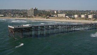 DCA08_147E - 4K aerial stock footage of flying by beach to orbit Crystal Pier, flyby beachside condos in Pacific Beach, California