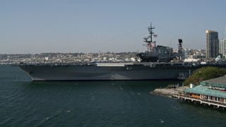 DCA08_196E - 4K aerial stock footage tilt from fishing boats to reveal and orbit an aircraft carrier, the USS Midway, Downtown San Diego, California