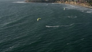 DCA08_236E - 4K aerial stock footage approach kite surfers near coastal homes, Pacific Beach, California
