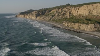 DCA08_255E - 4K aerial stock footage of flying by waves rolling toward the beach below cliffs, La Jolla, California