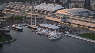 DCA08_296 - 4K aerial stock footage of yachts docked by convention center, Downtown San Diego, California, Sunset