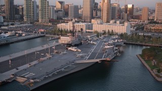DCA08_306 - 4K aerial stock footage orbit the aircraft carrier, USS Midway, in Downtown San Diego, California, Sunset