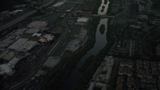 DCA08_334 - 4K aerial stock footage of a reverse view of a strip mall by the San Diego River, Mission Valley, California, twilight