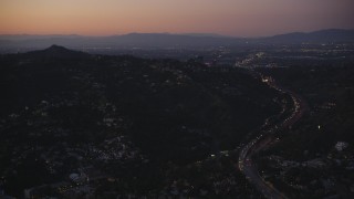 DCLA_276 - 5K stock footage aerial video of Highway 101 through the Hollywood Hills near hillside homes at twilight, California