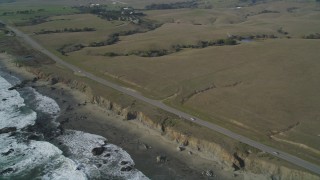 DCSF03_016 - 5K aerial stock footage Flyby Highway 1 on the California coast and pan left to ocean waves and an empty beach, San Simeon, California