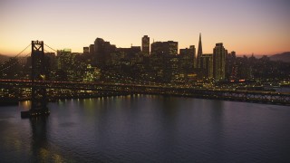 DCSF07_098 - Aerial stock footage of 5K Aerial Video Flying by the Bay Bridge, skyline in the background, Downtown San Francisco, California, twilight
