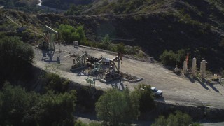 DFKSF01_018 - 5K aerial stock footage of orbiting around working oil rigs on a hilltop, Santa Paula, California