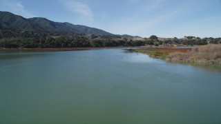 DFKSF01_057 - 5K aerial stock footage of flying over the lake as flock of birds take flight, Lake Cachuma, California