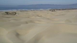 DFKSF02_027 - 5K aerial stock footage of panning across sand dunes, revealing ATV riders, Pismo Dunes, California