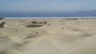 DFKSF02_028 - 5K aerial stock footage of orbiting ATV riders on coastal sand dunes, Pismo Dunes, California