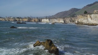 DFKSF02_038 - 5K aerial stock footage of flying low over waves, reveal rock formations, coastal cliffs, Shell Beach, California