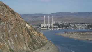 DFKSF03_002 - 5K aerial stock footage of flying by the Dynegy Power Plant, eclipsed by Morro Rock, Morro Bay, California