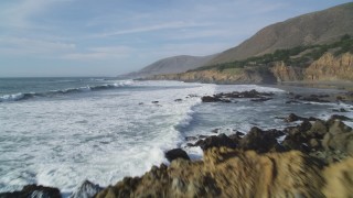 DFKSF03_027 - 5K aerial stock footage of flying low over waves crashing into rocks along the coast, Harmony, California