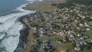 DFKSF03_041 - 5K stock footage aerial video of a bird's eye view of rugged coastal cliffs, tilt to homes near ocean, Cambria, California