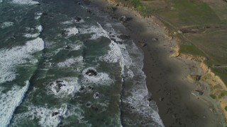 DFKSF03_048 - 5K aerial stock footage tilt from ocean to reveal isolated beachfront mansion, Cambria, California