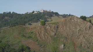 DFKSF03_060 - 5K aerial stock footage of approaching rocky hillside, Hearst Castle in the distance, San Simeon, California
