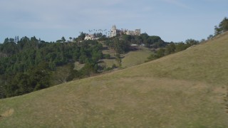 DFKSF03_071 - 5K aerial stock footage of a wide view of Hearst Castle, eclipsed by a hill, San Simeon, California