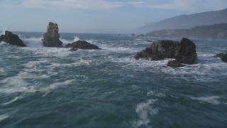 DFKSF03_077 - 5K aerial stock footage of flying over rock formations and waves off the coast, San Simeon, California