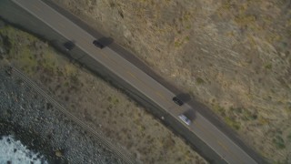 DFKSF03_090 - 5K aerial stock footage of a bird's eye view of black cars on Highway 1, above coastal cliffs, Big Sur, California