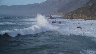DFKSF03_105 - 5K stock footage aerial video of flying over tall waves, approaching coastal rock formations, Big Sur, California