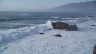 DFKSF03_106 - 5K aerial stock footage of panning across tall waves crashing into rock formations, Big Sur, California
