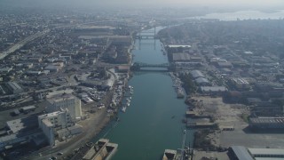 DFKSF05_099 - 5K aerial stock footage fly over the Oakland Estuary toward bridges and factories, Oakland, California