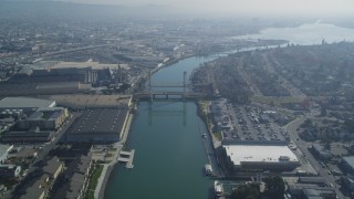 DFKSF05_100 - 5K aerial stock footage follow Oakland Estuary, approach bridges and waterfront factories, Oakland, California