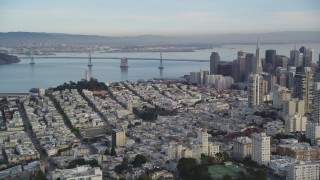 DFKSF06_168 - 5K aerial stock footage approach Coit Tower, Bay Bridge, pan skyscrapers in Downtown San Francisco, California