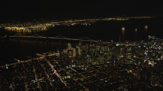 DFKSF07_063 - 5K aerial stock footage of a high altitude view of Bay Bridge and skyscrapers in Downtown San Francisco, California, night