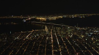 DFKSF07_065 - 5K aerial stock footage of a high altitude view of Coit Tower, the Bay Bridge, and skyscrapers in Downtown San Francisco, California, night