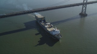 DFKSF09_050 - 5K aerial stock footage fly away from a cargo ship sailing under the Bay Bridge, San Francisco, California